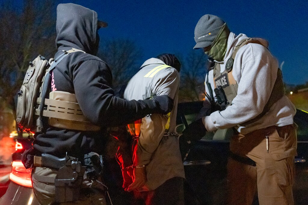U.S. Immigration and Customs Enforcement officers use a chain to more comfortably restrain a detained person using handcuffs positioned in front, Monday, Jan. 27, 2025, in Silver Spring, Md.