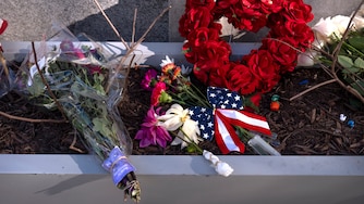 A small memorial of flags, flowers, other items are seen in a planter, Friday, Nov. 28, 2025, near the site where two National Guard members were shot in Washington. (AP Photo/Mark Schiefelbein)