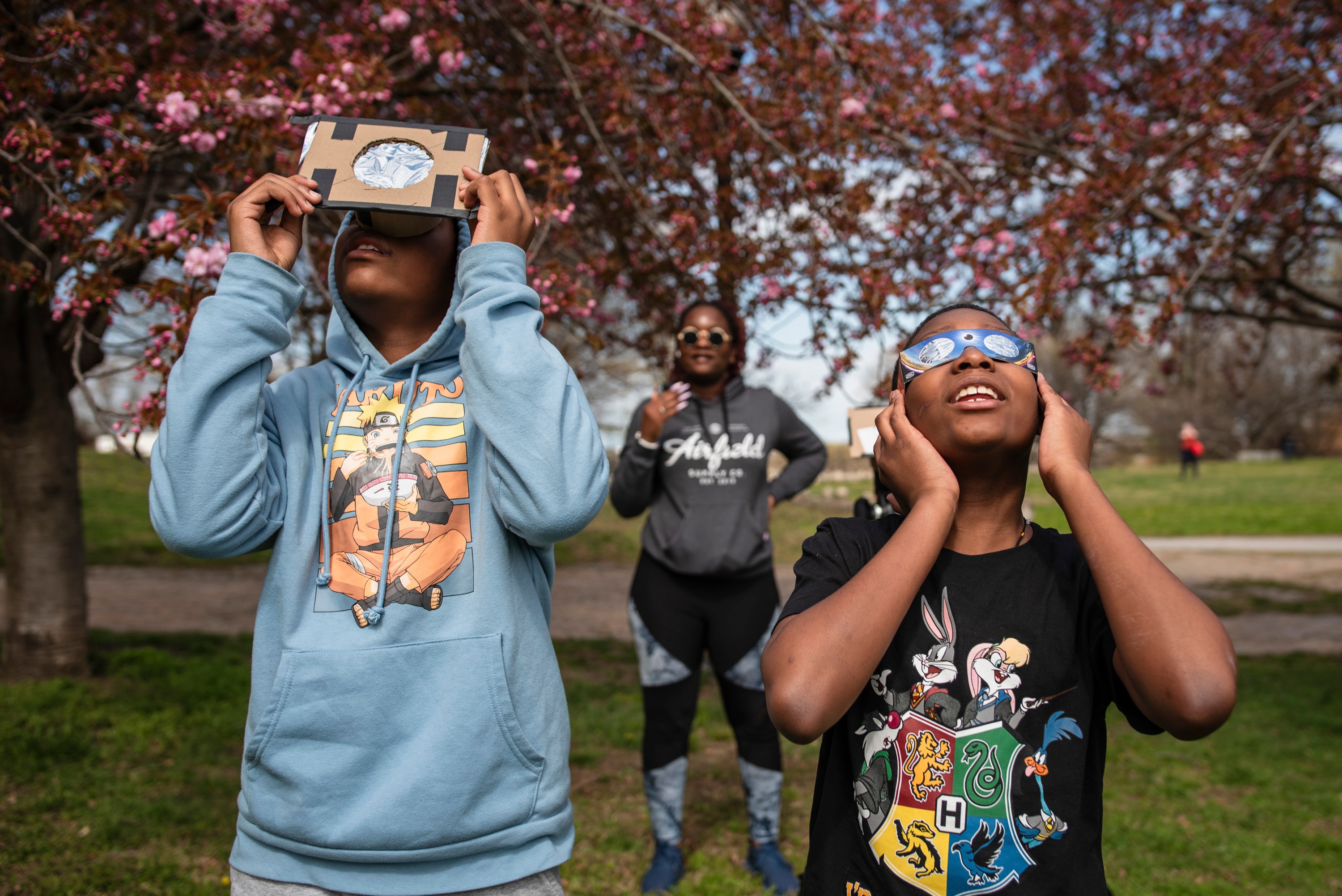 Baltimore residents, Emmanuel Stewart and Isaac Stewart, view the eclipse at its peak from Patterson Park in Baltimore, MD on 4.8.2024.