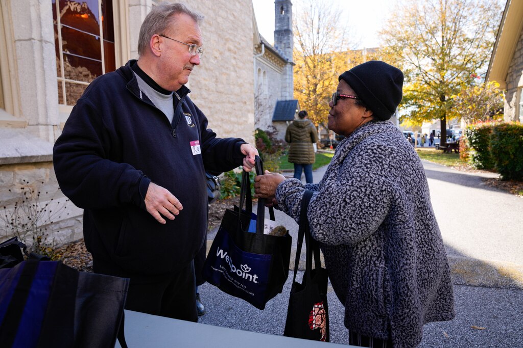 Volunteer Ron Conley, left, hands bags of food to Linda Emmanuel during a Thanksgiving holiday meal giveaway at Trinity Episcopal Church in Towson, Md., on Monday, November 24, 2025. The Assistance Center of Towson Churches organized the event, which was also held in 2024.